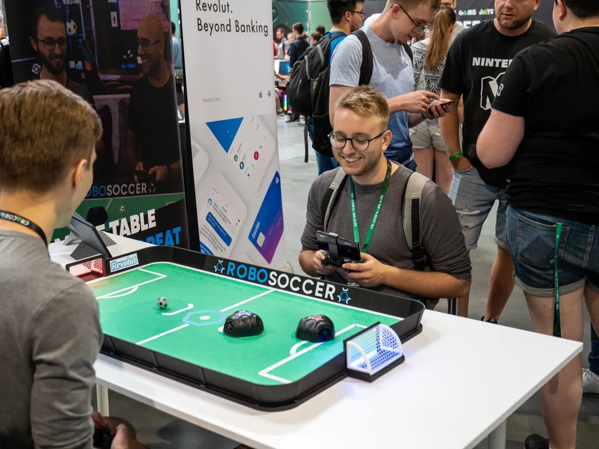 People playing RoboSoccer with gamepads at a public tech event